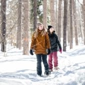 Two students snowshoeing in the woods.