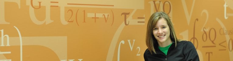 Student smiling with a wall filled with equations