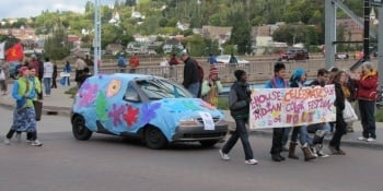 Indian students walking in the parade next to a decorated car.